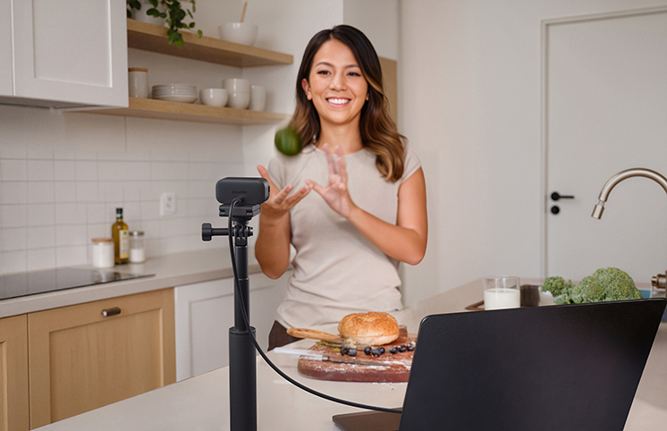 Woman streams from kitchen using Insta360 Link 2 Pro AI webcam.